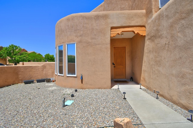 property entrance featuring stucco siding and fence