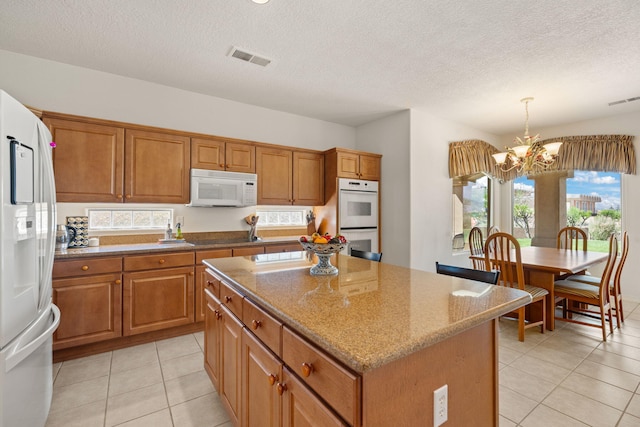 3916 Alamogordo Dr NW, Albuquerque, NM 87120 - kitchen with white appliances, a chandelier, brown cabinets, a center island, and light tile patterned floors