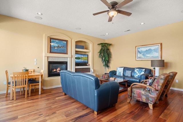 3916 Alamogordo Dr NW, Albuquerque, NM 87120 - living room featuring a textured ceiling, a glass covered fireplace, wood finished floors, a ceiling fan, and baseboards