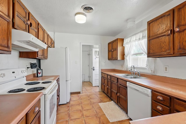 1595 W Bosque Loop, Bosque Farms, NM 87068 - kitchen with white appliances, under cabinet range hood, light countertops, brown cabinets, and a textured ceiling