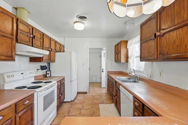 1595 W Bosque Loop, Bosque Farms, NM 87068 - kitchen with white appliances, under cabinet range hood, light countertops, brown cabinets, and light tile patterned floors