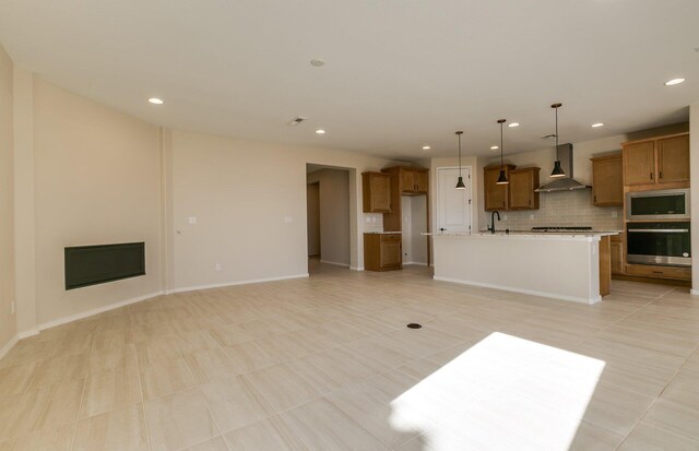 8328 Bronte Ln NW, Albuquerque, NM 87120 - kitchen featuring stainless steel appliances, wall chimney range hood, brown cabinets, tasteful backsplash, and open floor plan