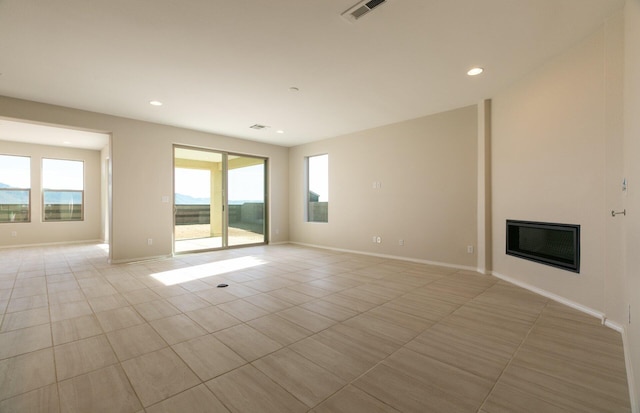 8328 Bronte Ln NW, Albuquerque, NM 87120 - empty room featuring plenty of natural light, a glass covered fireplace, recessed lighting, and light tile patterned floors