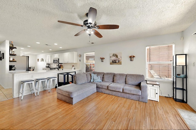 1250 Carnival Ave NW, Los Lunas, NM 87031 - living room with a textured ceiling, light wood-style floors, a ceiling fan, recessed lighting, and baseboards