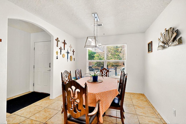 1250 Carnival Ave NW, Los Lunas, NM 87031 - dining area featuring light tile patterned floors, arched walkways, and a textured ceiling