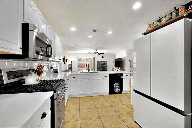 1250 Carnival Ave NW, Los Lunas, NM 87031 - kitchen with stainless steel appliances, a peninsula, a sink, ceiling fan, and a textured ceiling