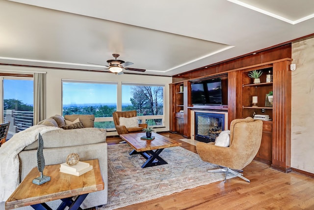 1106 Warm Sands Dr SE, Albuquerque, NM 87123 - living area with a fireplace with flush hearth, light wood-style floors, a ceiling fan, baseboards, and a tray ceiling