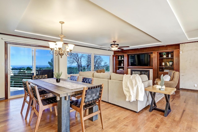 1106 Warm Sands Dr SE, Albuquerque, NM 87123 - dining space with a tray ceiling, a chandelier, light wood-style flooring, and a ceiling fan