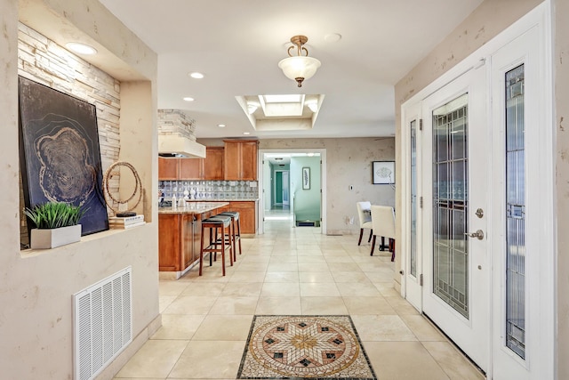 1106 Warm Sands Dr SE, Albuquerque, NM 87123 - kitchen with brown cabinetry, a kitchen breakfast bar, light countertops, a skylight, and decorative backsplash