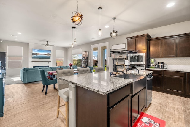kitchen with recessed lighting, appliances with stainless steel finishes, backsplash, dark brown cabinets, and an island with sink