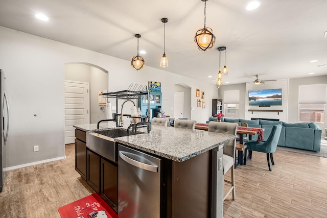 kitchen featuring stainless steel appliances, arched walkways, light wood-style floors, ceiling fan, and hanging light fixtures
