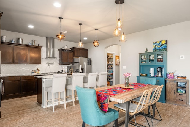 dining room featuring light wood-style flooring, arched walkways, and recessed lighting