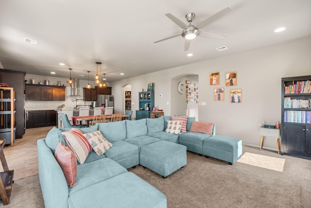 living area with arched walkways, recessed lighting, ceiling fan, and light carpet