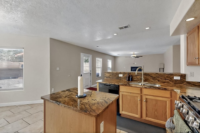 5727 Cibola Dr NE, Rio Rancho, NM 87144 - kitchen featuring a peninsula, stainless steel range with gas stovetop, dark stone counters, ceiling fan, and a center island