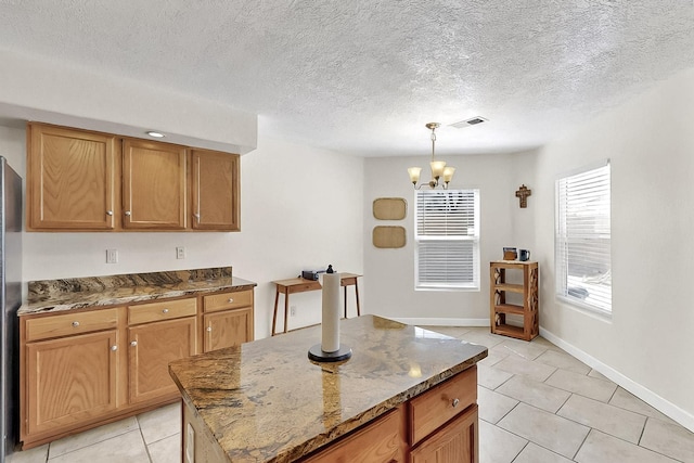 5727 Cibola Dr NE, Rio Rancho, NM 87144 - kitchen featuring light tile patterned floors, a chandelier, dark stone counters, pendant lighting, and a kitchen island
