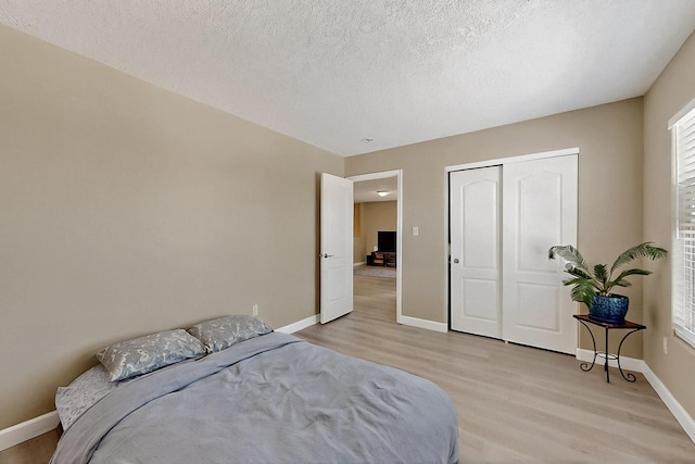 5727 Cibola Dr NE, Rio Rancho, NM 87144 - bedroom with light wood finished floors, a closet, multiple windows, and a textured ceiling