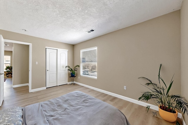 5727 Cibola Dr NE, Rio Rancho, NM 87144 - bedroom featuring light wood-type flooring, multiple windows, a closet, and a textured ceiling