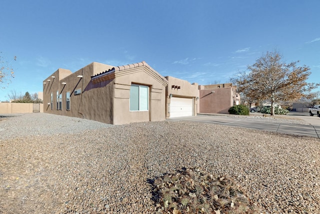 10216 Sand Sage Dr NW, Albuquerque, NM 87114 - view of side of home featuring driveway, an attached garage, and stucco siding