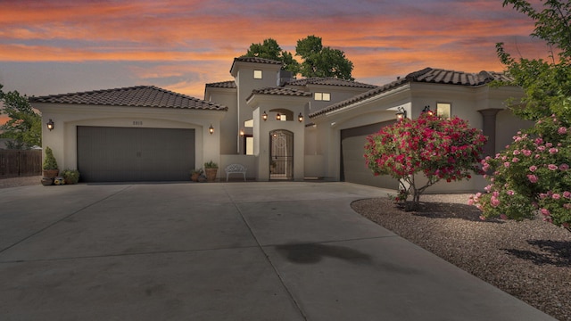 2815 Linda Pl SW, Albuquerque, NM 87105 - mediterranean / spanish house featuring an attached garage, driveway, stucco siding, and a tile roof