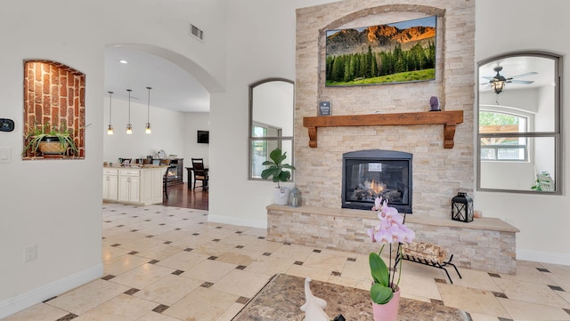 2815 Linda Pl SW, Albuquerque, NM 87105 - living area with baseboards, ceiling fan, a stone fireplace, a towering ceiling, and arched walkways