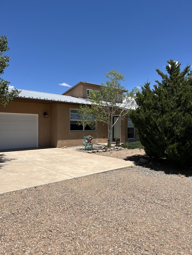 21 Camino No Mas, Stanley, NM 87056 - view of front facade featuring stucco siding, driveway, a garage, and a metal roof