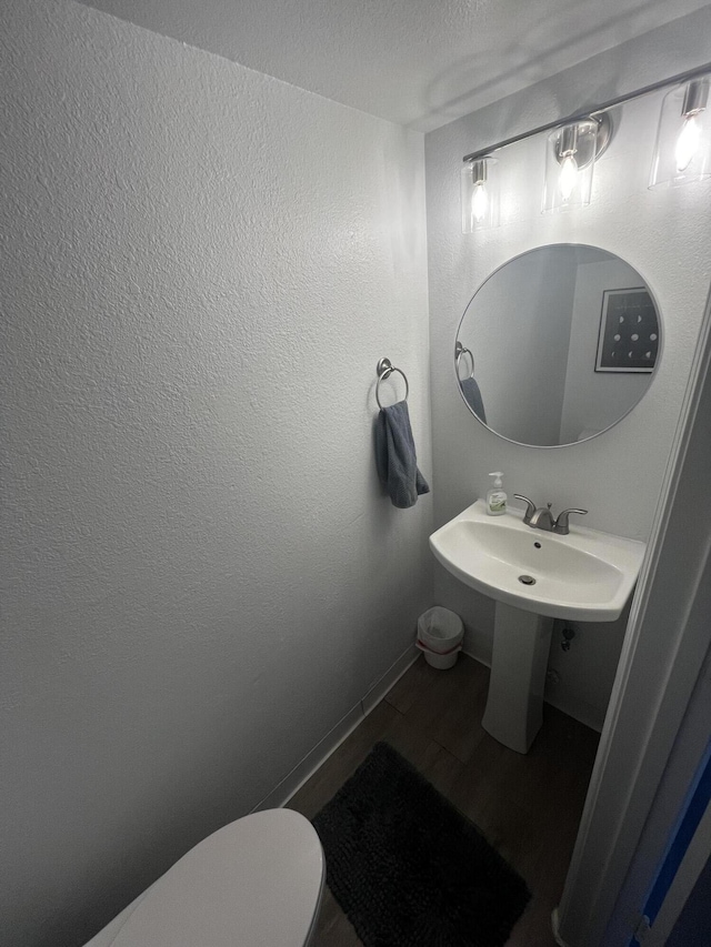 3301 Monroe St NE Unit D45, Albuquerque, NM 87110 - half bathroom featuring wood finished floors, toilet, baseboards, a textured ceiling, and a sink