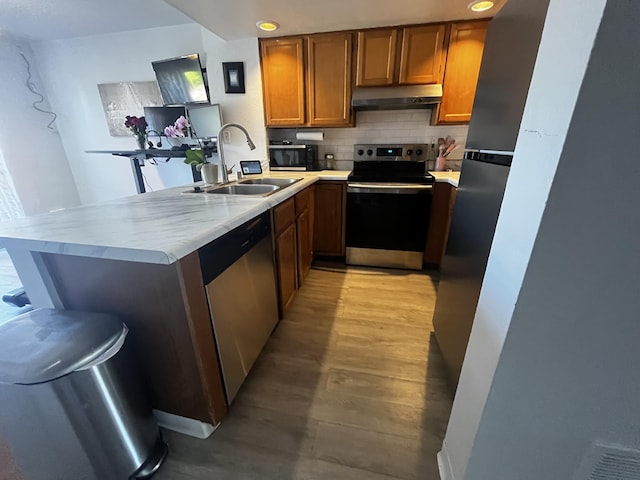 3301 Monroe St NE Unit D45, Albuquerque, NM 87110 - kitchen featuring stainless steel appliances, a sink, under cabinet range hood, brown cabinets, and a peninsula
