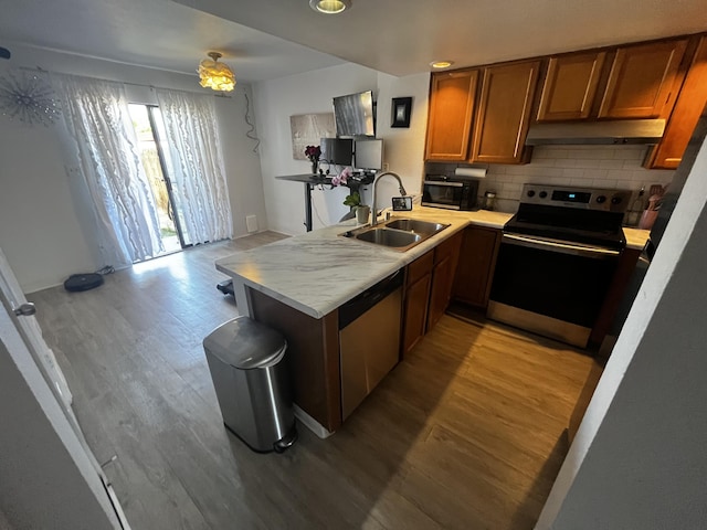 3301 Monroe St NE Unit D45, Albuquerque, NM 87110 - kitchen featuring appliances with stainless steel finishes, a sink, a peninsula, light wood-style floors, and brown cabinets
