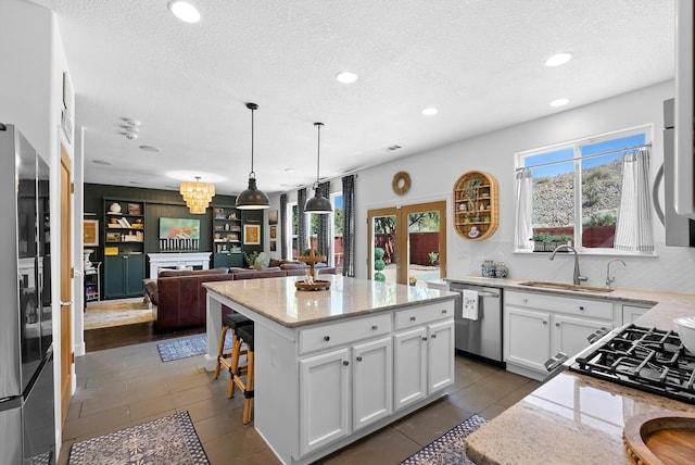 3515 Colina Serena Pl NE, Rio Rancho, NM 87124 - kitchen featuring appliances with stainless steel finishes, a sink, light stone countertops, a textured ceiling, and white cabinets