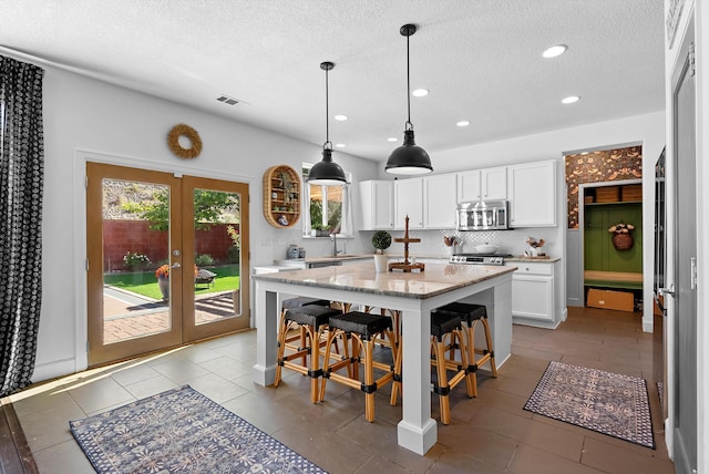 3515 Colina Serena Pl NE, Rio Rancho, NM 87124 - kitchen with stainless steel microwave, white cabinets, a kitchen island, a kitchen breakfast bar, and recessed lighting