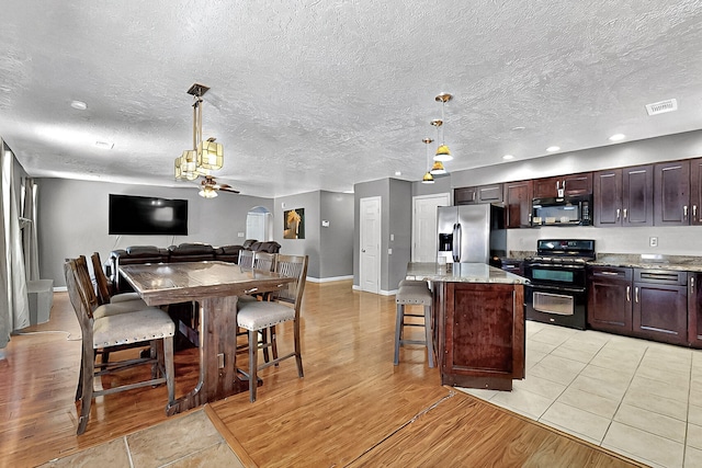 1905 Clearwater Loop NE, Rio Rancho, NM 87144 - kitchen with black appliances, a center island, pendant lighting, dark brown cabinetry, and a textured ceiling