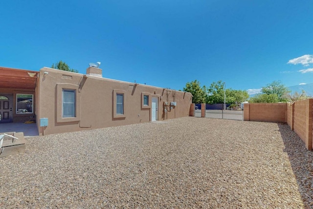 501 Calle De La Angel, Bernalillo, NM 87004 - rear view of house with stucco siding, a chimney, and a gate