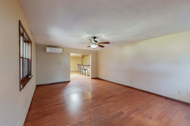 501 Calle De La Angel, Bernalillo, NM 87004 - empty room featuring wood finished floors, a wall mounted air conditioner, ceiling fan, a textured ceiling, and baseboards
