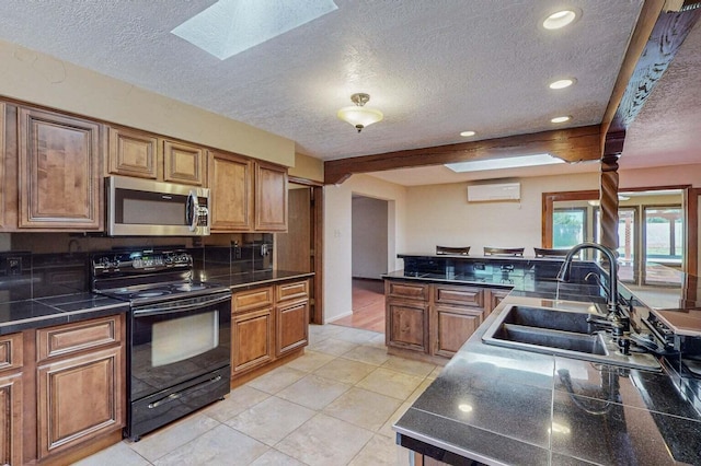 501 Calle De La Angel, Bernalillo, NM 87004 - kitchen with stainless steel microwave, black range with electric stovetop, a sink, a skylight, and a wall unit AC