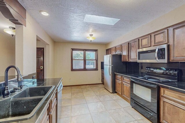 501 Calle De La Angel, Bernalillo, NM 87004 - kitchen with stainless steel appliances, a sink, a skylight, a textured ceiling, and brown cabinetry