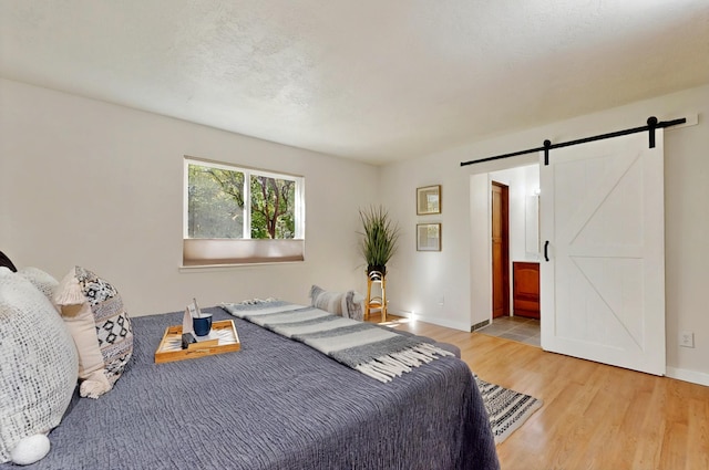 9737 Academy St NW, Albuquerque, NM 87114 - bedroom with a barn door, wood finished floors, baseboards, and ensuite bath