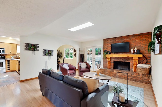 9737 Academy St NW, Albuquerque, NM 87114 - living room featuring light wood finished floors, a fireplace, baseboards, and arched walkways
