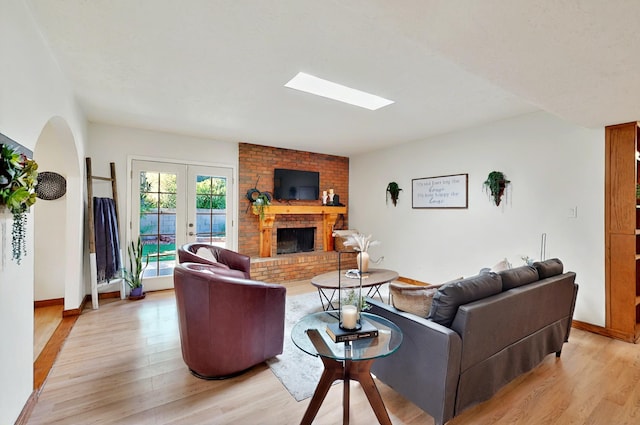 9737 Academy St NW, Albuquerque, NM 87114 - living room with light wood-style flooring, a skylight, a brick fireplace, and baseboards