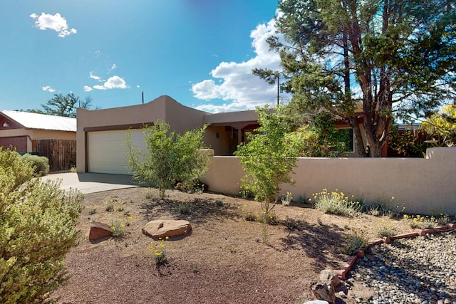 9737 Academy St NW, Albuquerque, NM 87114 - pueblo-style house with a fenced front yard, stucco siding, a garage, and concrete driveway