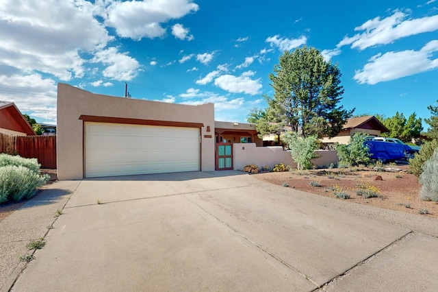 9737 Academy St NW, Albuquerque, NM 87114 - pueblo-style house with stucco siding, a garage, concrete driveway, and a gate