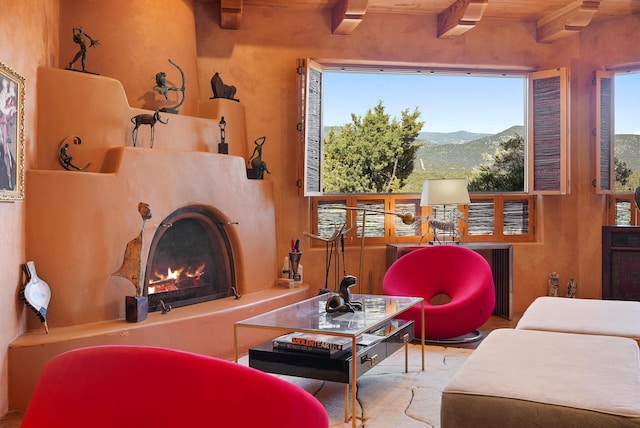 28 Canon Escondido, Sandia Park, NM 87047 - living room featuring a mountain view, beam ceiling, and a warm lit fireplace