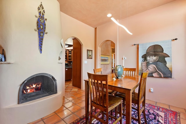28 Canon Escondido, Sandia Park, NM 87047 - dining area with arched walkways, light tile patterned floors, a lit fireplace, and recessed lighting