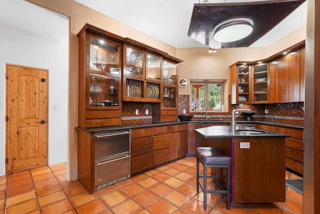 28 Canon Escondido, Sandia Park, NM 87047 - kitchen with a sink, decorative backsplash, brown cabinets, and a kitchen island with sink