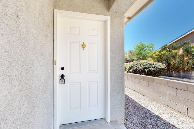 9927 Silverton Dr NW, Albuquerque, NM 87114 - view of exterior entry with stucco siding and fence