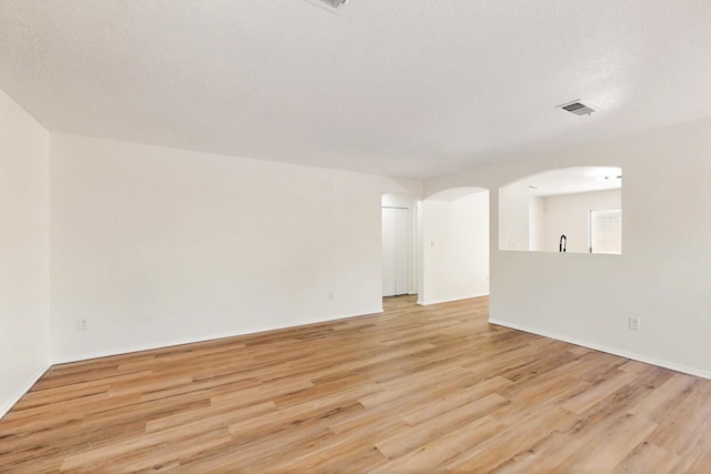 9927 Silverton Dr NW, Albuquerque, NM 87114 - spare room with light wood-style floors, arched walkways, and baseboards
