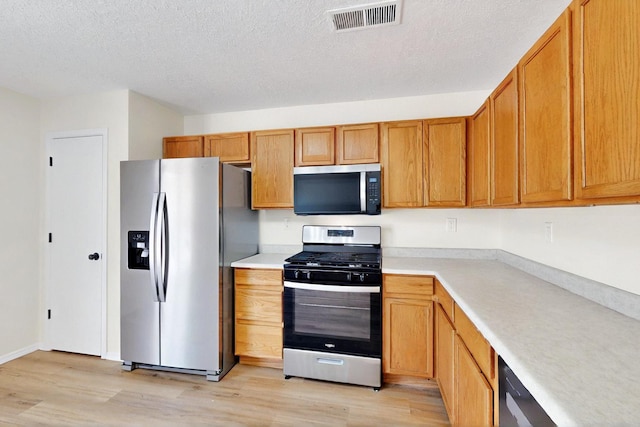 9927 Silverton Dr NW, Albuquerque, NM 87114 - kitchen with appliances with stainless steel finishes, light wood-style floors, light countertops, a textured ceiling, and brown cabinetry