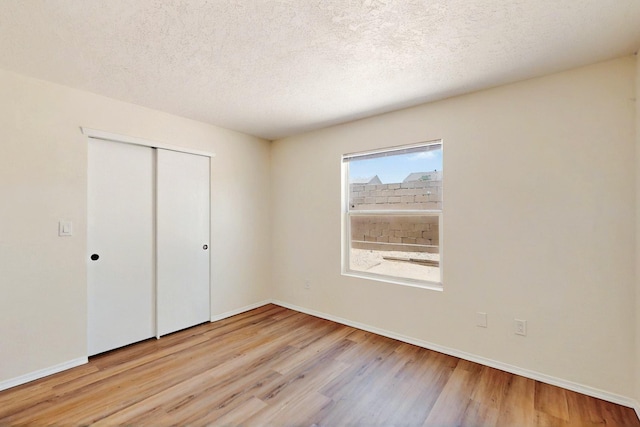 9927 Silverton Dr NW, Albuquerque, NM 87114 - unfurnished bedroom with light wood-style floors, a closet, baseboards, and a textured ceiling