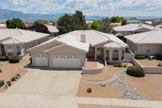 10320 Durham St NW, Albuquerque, NM 87114 - mediterranean / spanish-style house featuring a garage, a tile roof, concrete driveway, stucco siding, and a mountain view