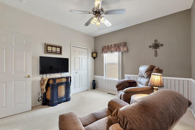 10320 Durham St NW, Albuquerque, NM 87114 - living room with carpet flooring, ceiling fan, a wood stove, and a wainscoted wall