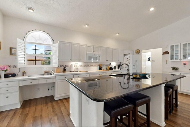 10320 Durham St NW, Albuquerque, NM 87114 - kitchen featuring white appliances, white cabinetry, wood finished floors, a kitchen bar, and vaulted ceiling